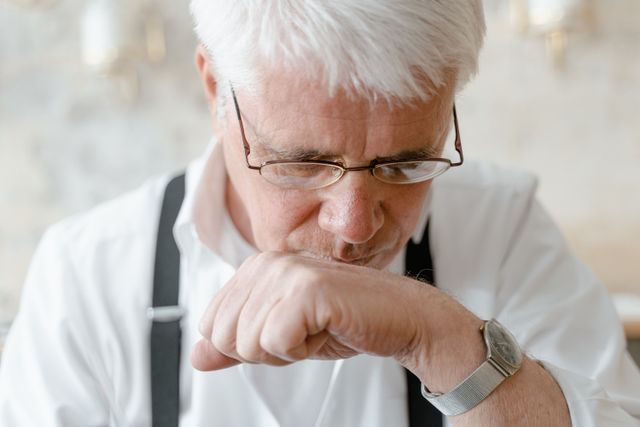 Older man with glasses resting his chin on his hand