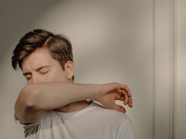 Person coughing into their elbow